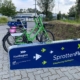 Auf dem Foto ist die Leihfahrradstation der SpottenFlotte zu sehen. Zwei grüne Fahrräder sind hier abgestellt.