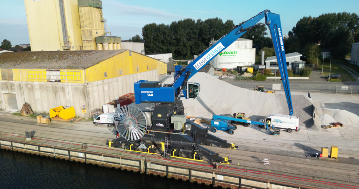 Kreishafen Rendsburg. An der Kaikante steht ein großes Umschlagsgerät, das gerade Kalk umschlägt.
