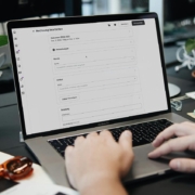 Aufgeklapptes Laptop an dem ein Mensch arbeitet. Man sieht aber nur die Hände.